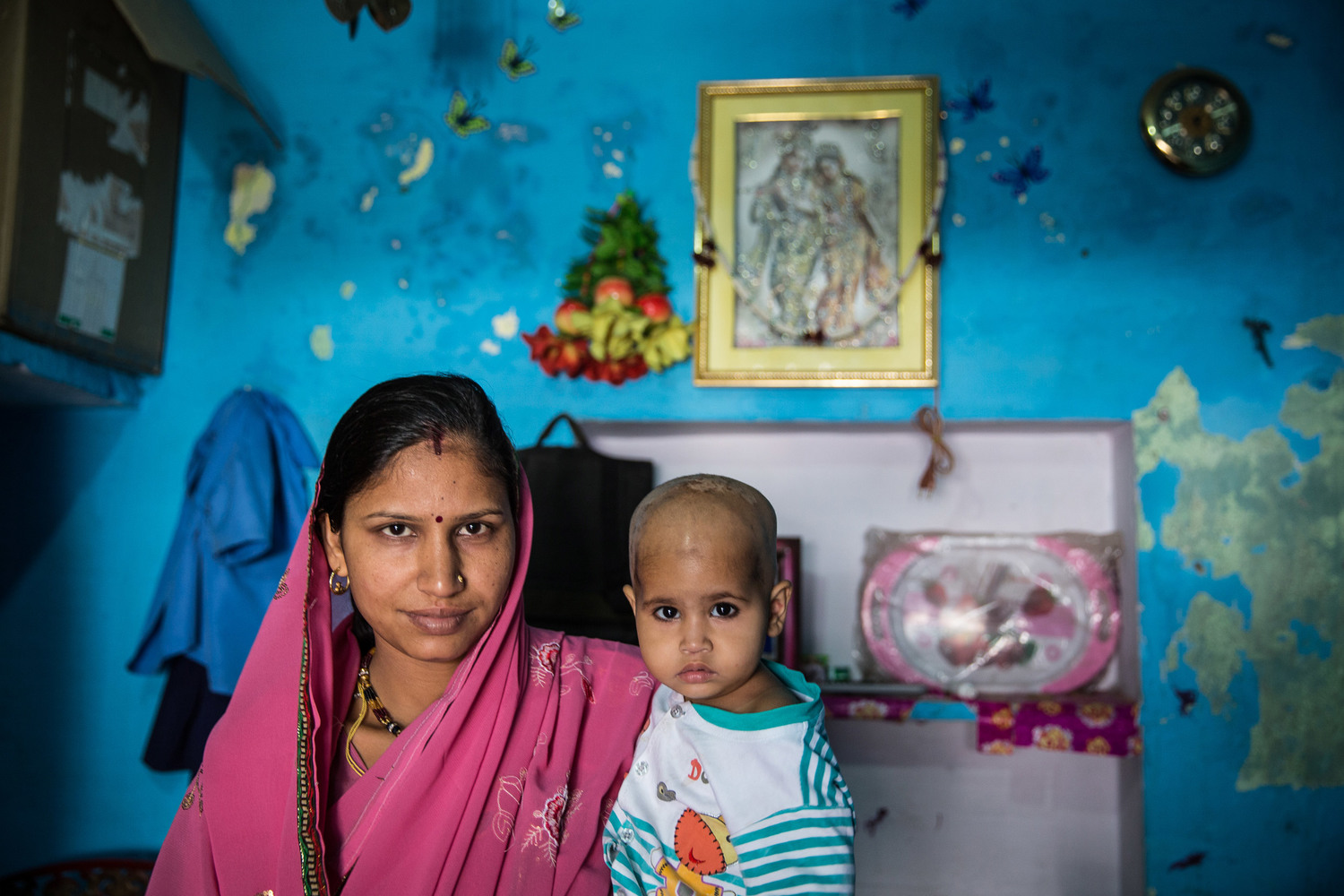  Shushila Meena, 26, stands in her home with one of her three children. Her husband is a tuk tuk driver. 