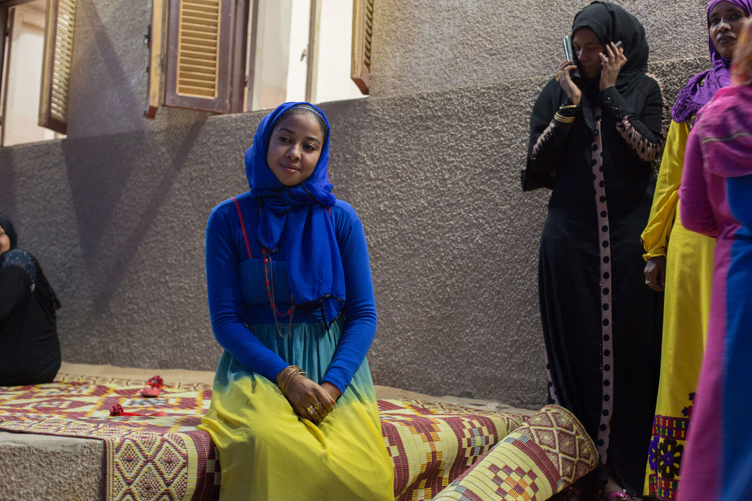  While her groom and father are signing the marriage contract in the mosque, the bride sits outside her home with her friends and family members. 